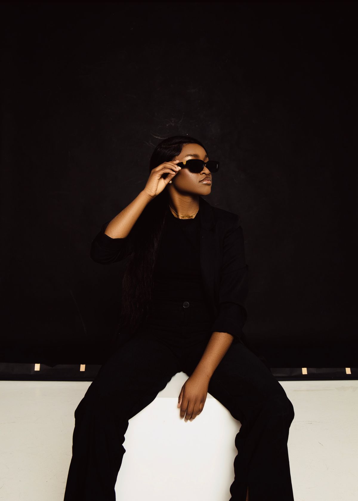A woman in a black suit and sunglasses